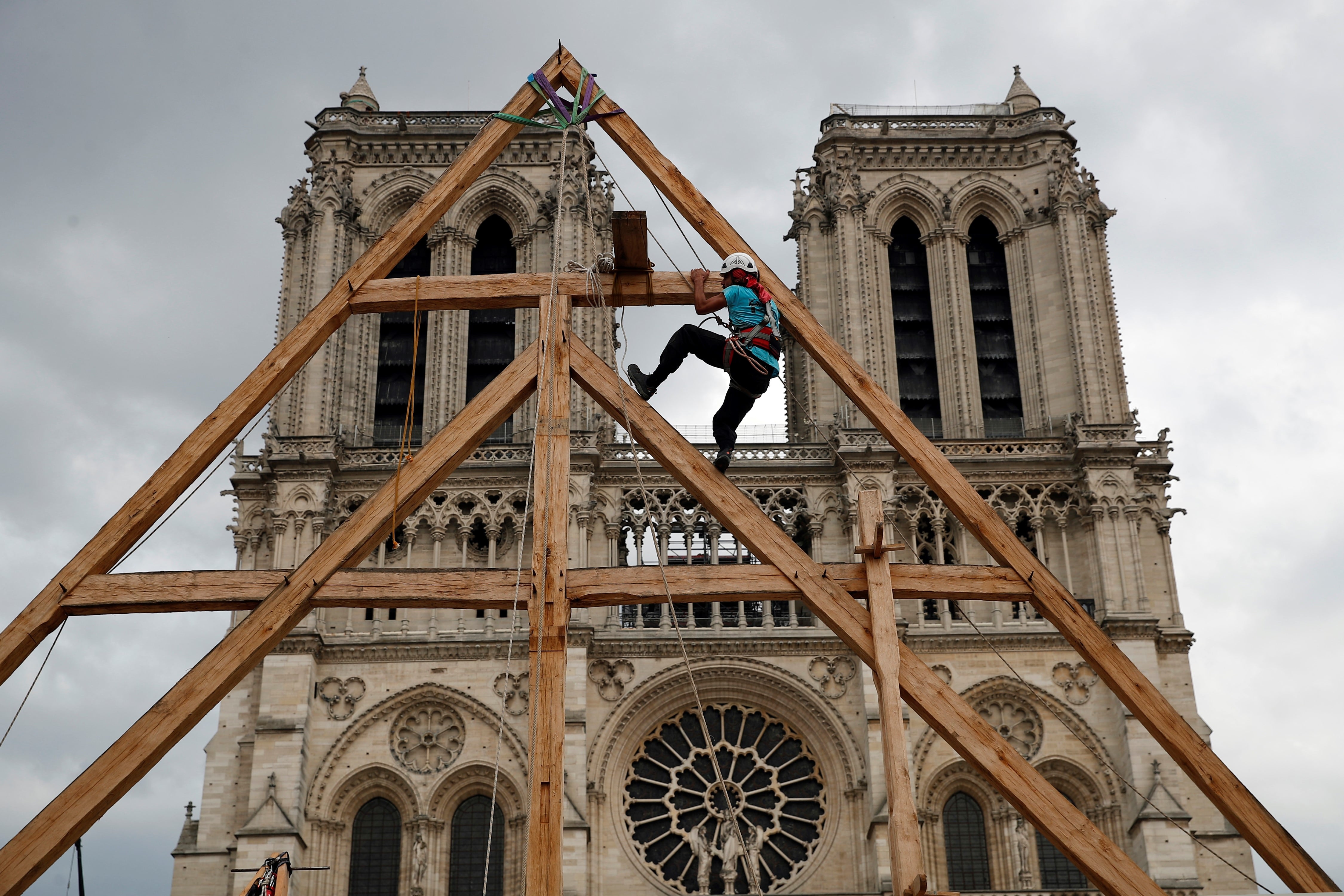 Charles, uno de los carpinteros, muestra las habilidades de sus colegas medievales en la plaza frente a la catedral de Notre Dame en París, Francia, el sábado 19 de septiembre de 2020, el día en que se honra la herencia europea, al reproducir para el público una sección. de la elaborada carpintería utilizada cuando se construyó el edificio. Las elaboradas vigas de madera se incendiaron en un devastador incendio de abril que también derribó la aguja de la catedral, que ahora está siendo renovada. (Foto AP / Francois Mori)