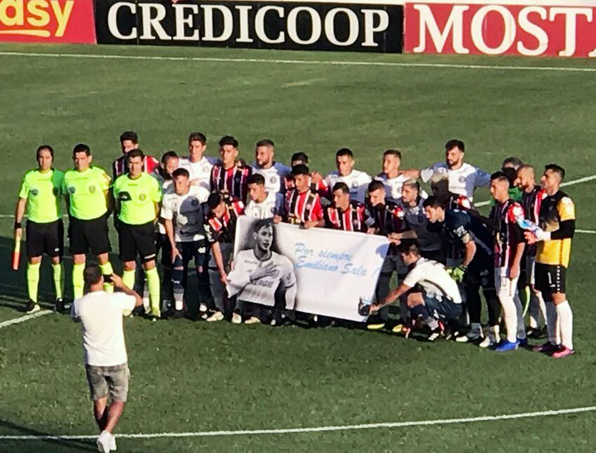 
Homenaje. Ambos equipos y posaron con una bandera de Emi Sala. | Gentileza
   