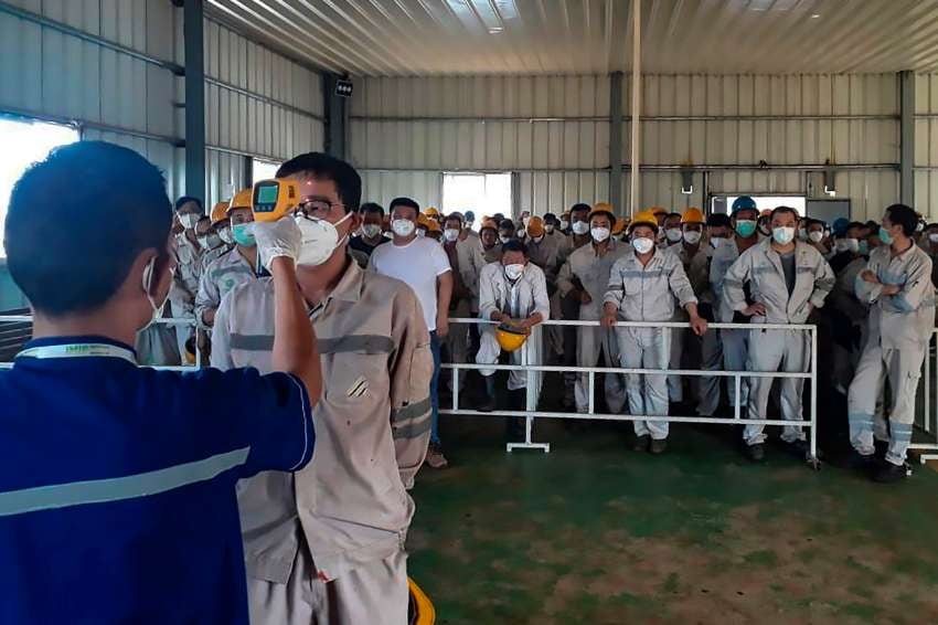 
Un funcionario de salud controla la temperatura corporal de un trabajador en el Parque Industrial PT en Indonesia. | AFP
   