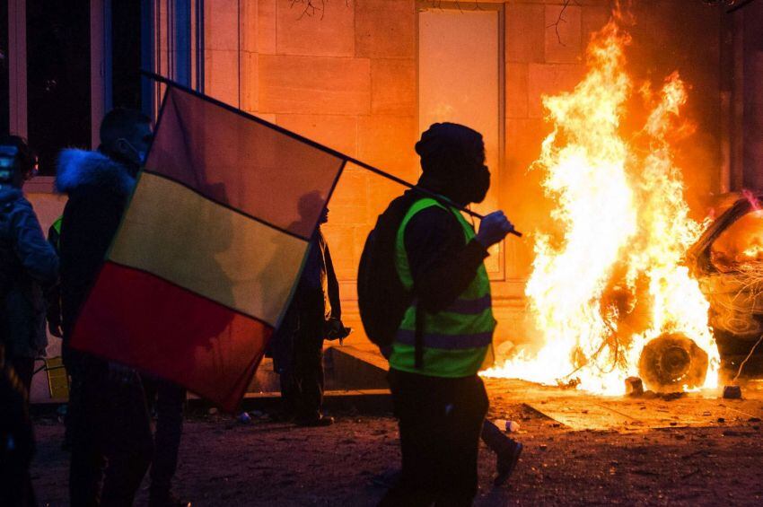 
Foto: AFP | Un manifestante sostiene una bandera francesa mientras se quema un vehículo, en el Jardín de las Tullerías, frente al Musée de l'Orangerie.
   