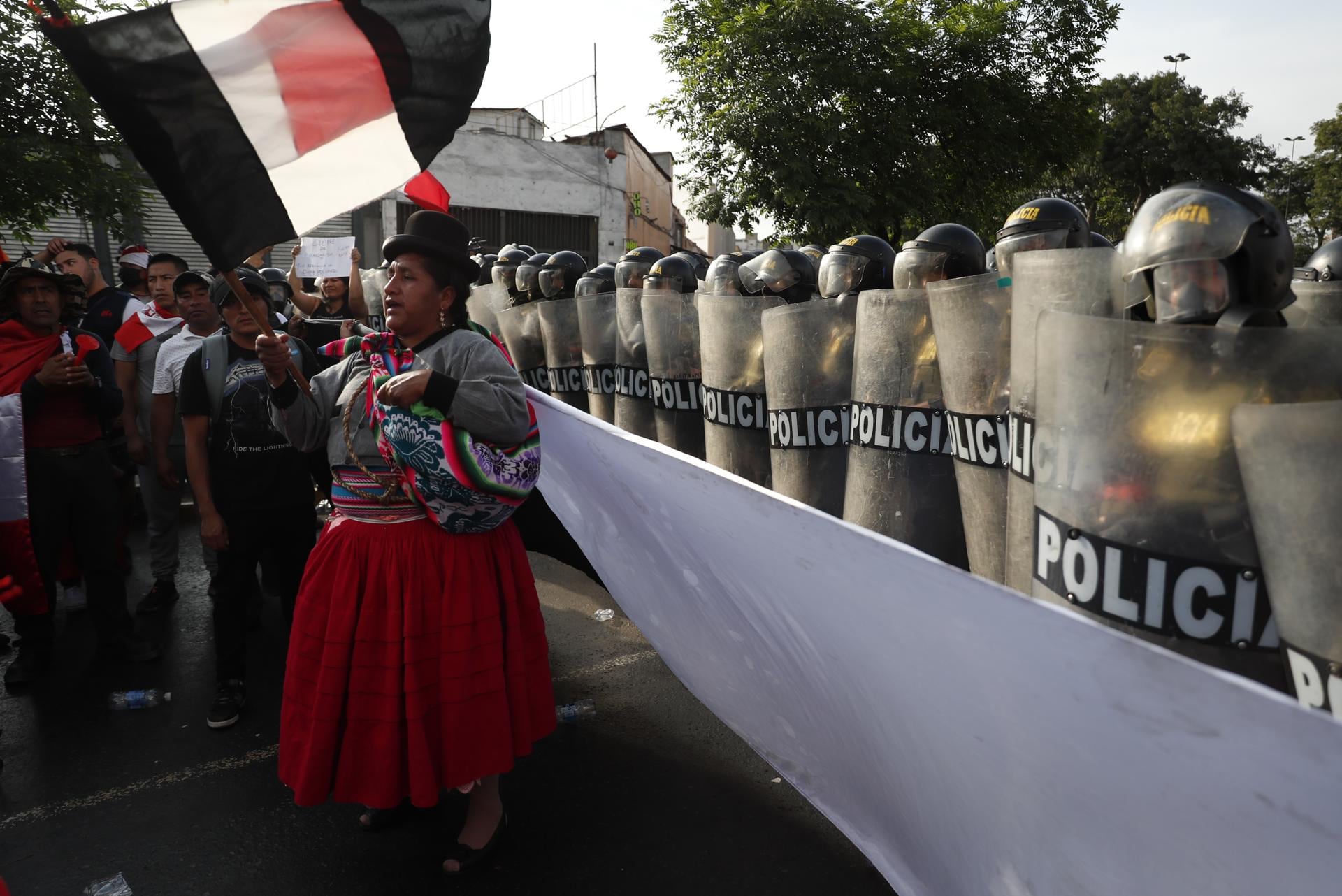 Una mujer participa en la marcha llamada la "toma de Lima" mientras miembros de la policía montan guardia hoy, en Lima (Perú). La gran marcha nacional denominada "la toma de Lima" ha activado una serie de acciones de protesta en distintos puntos del país, en donde los manifestantes exigen la renuncia de la presidenta Dina Boluarte y el cierre del Congreso, así como la convocatoria a elecciones generales para este año y a una asamblea constituyente. Foto: EFE/ Paolo Aguilar