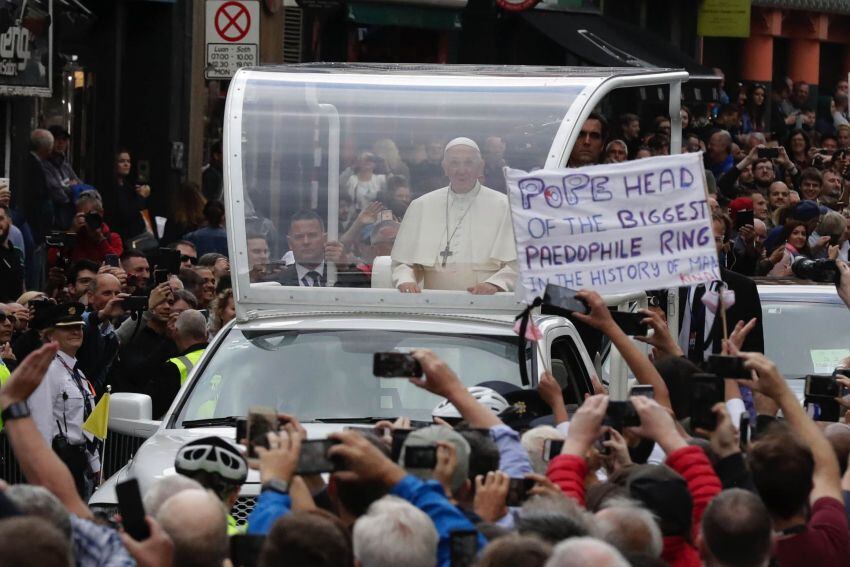 
    El Papa Francisco en Dublín, Irlanda, pasa frente a una pancarta de un manifestante que acusa a la Iglesia de ser la mayor red de pedófilos de la humanidad. 25 de agosto de 2018.
   