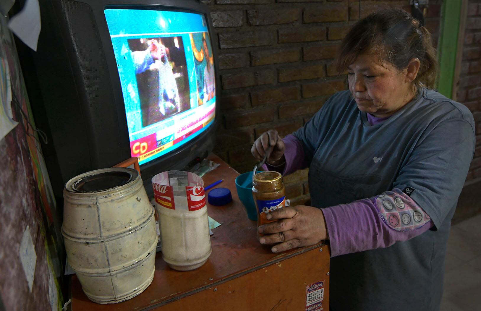 Rocío, para unos minutos para prepararse un café caliente en esta fría mañana. El televisor para hacer bulla nomás, nos dice. 
Foto: Orlando Pelichotti