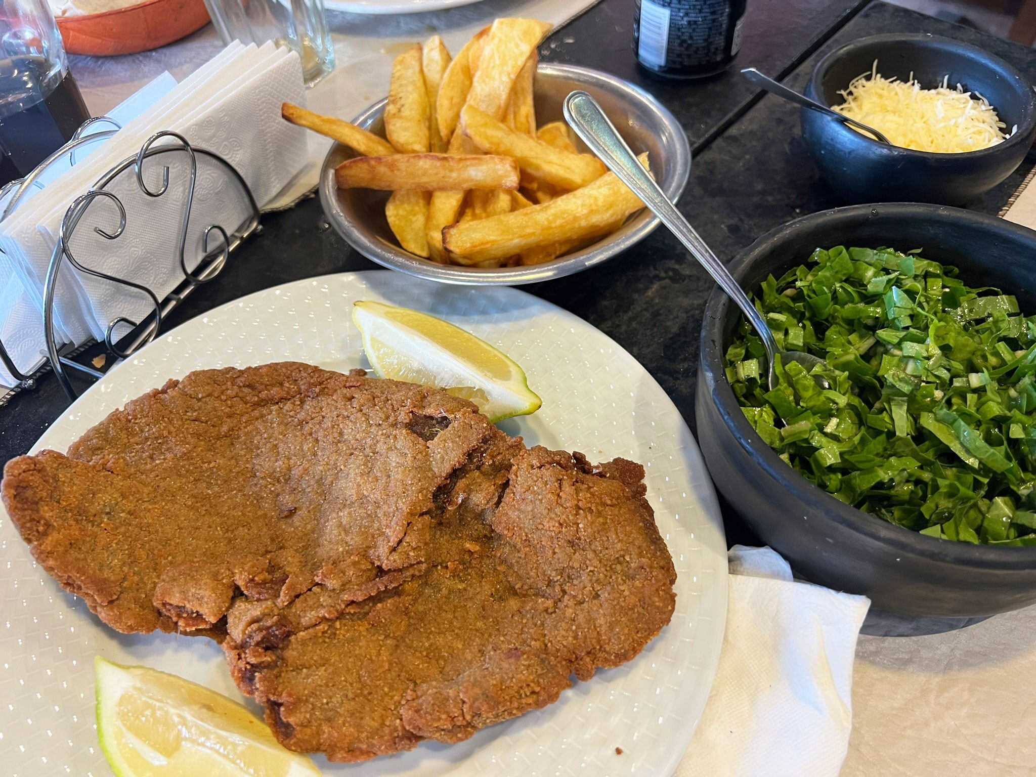 Milanesa con fritas y ensalada de achicoria y ajo.