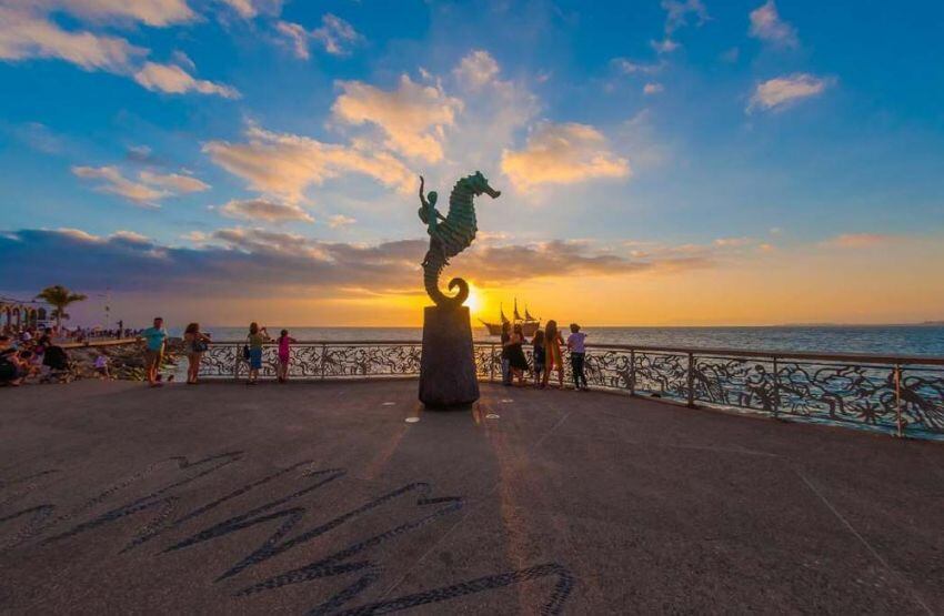 
    Atardecer y una de las esculturas del malecón, una galería de arte al aire libre en Puerto Vallarta.
   