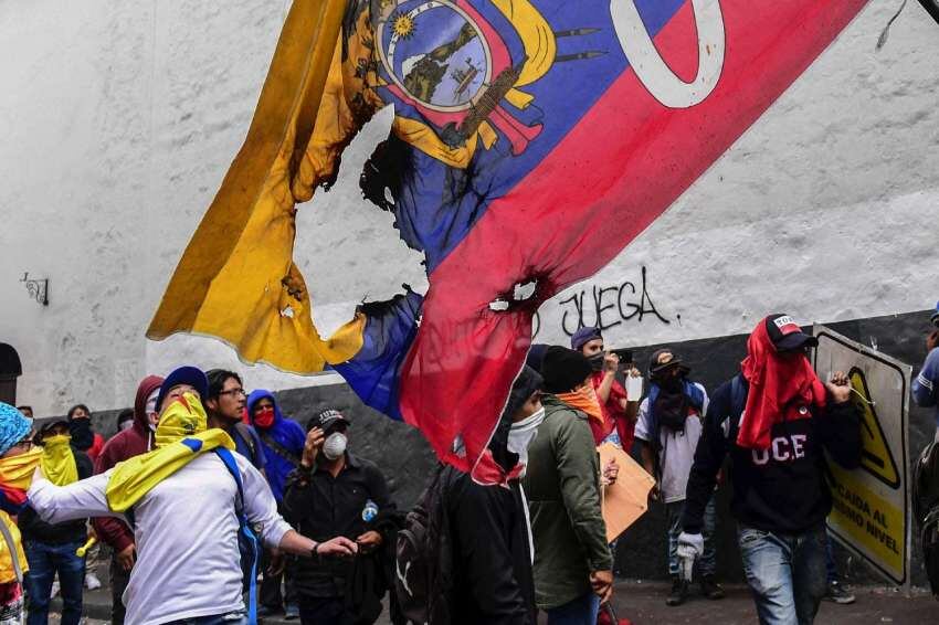 
Foto: AFP | Manifestantes marchan con una bandera de Ecuador quemada.
   