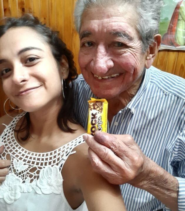 
    Aldana, su abuelo y el chocolate de regalo. / gentileza
   