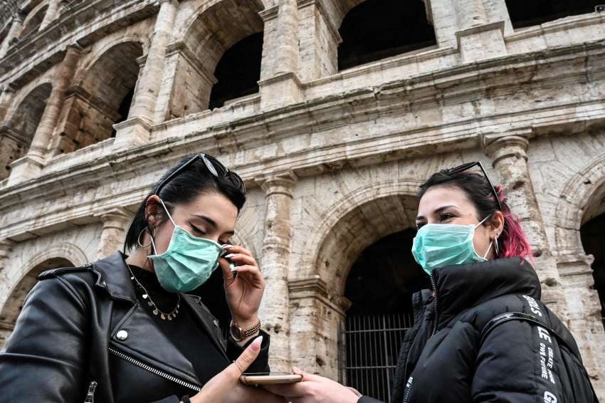 
Turistas con una máscara respiratoria protectora, recorren el Coliseo en Roma. | AFP
   