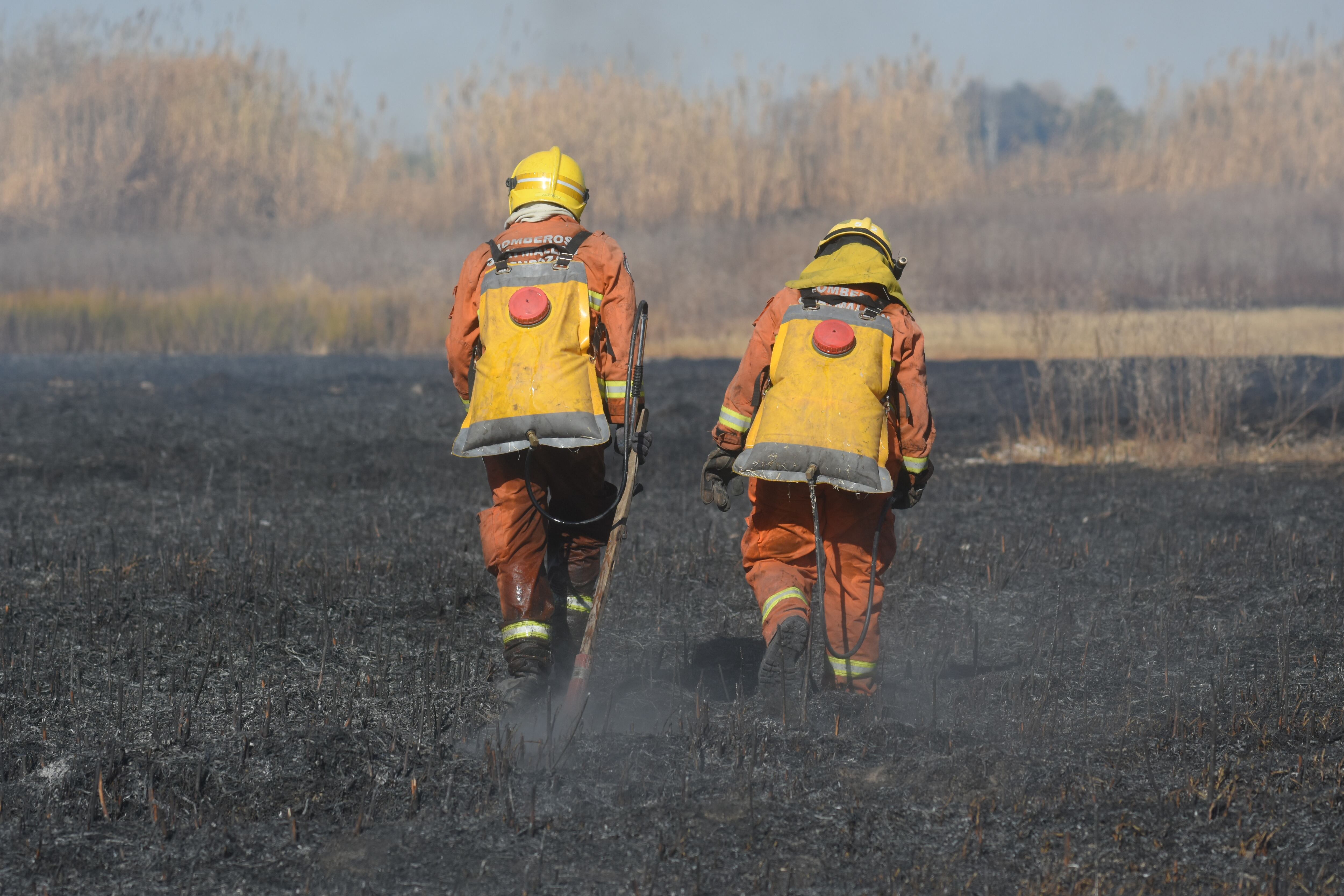 Bomberos del Plan de manejo del fuego caminan por los pastizales incendiados.