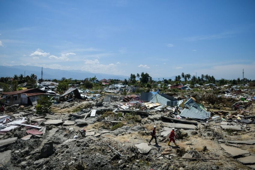 
     Dos rescatistas caminan entre el desastre que dejó el terremoto. / AFP
    