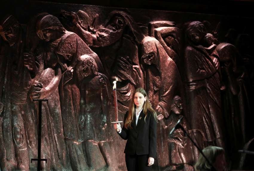 
Una niña sostiene una antorcha para encender una antorcha conmemorativa durante la ceremonia en el Foro Mundial del Holocausto | AP
   