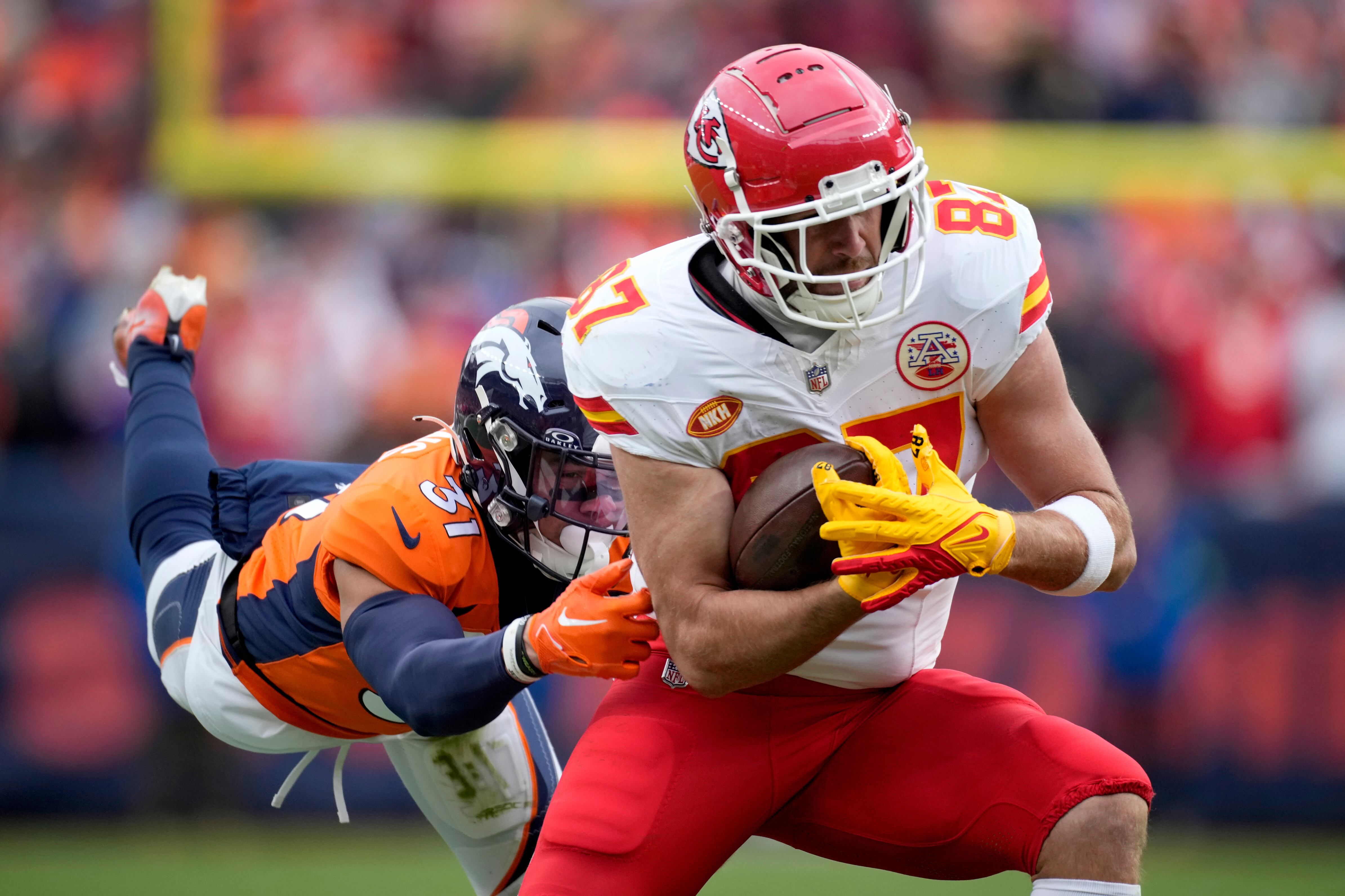 El tight end de los Chiefs de Kansas City Travis Kelce atrapa un mientras lo defiende el safety de los Broncos de Denver Justin Simmons en el encuentro del domingo 29 de octubre del 2023. (AP Foto/David Zalubowski)