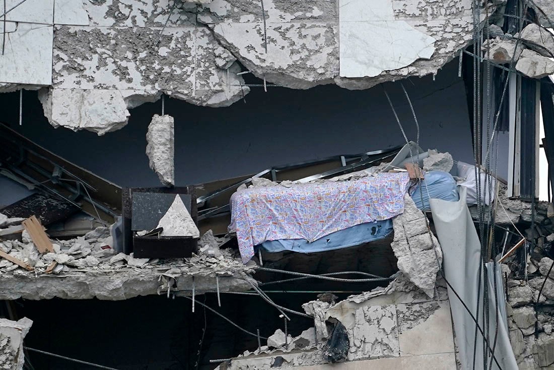 Una cama cuelga del edificio parcialmente destruido.