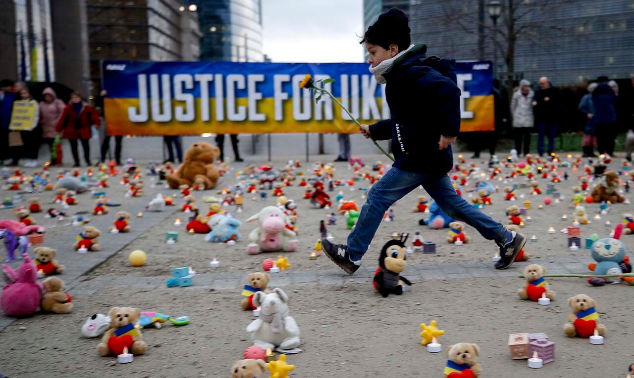 Un niño sostiene una flor mientras miembros de la ONG Avaaz y refugiados ucranianos colocan ositos de peluche en Bruselas, Bélgica. Según los organizadores, el evento fue para llamar la atención sobre la supuesta denuncia de secuestro de niños ucranianos por parte de Rusia. Foto: EFE