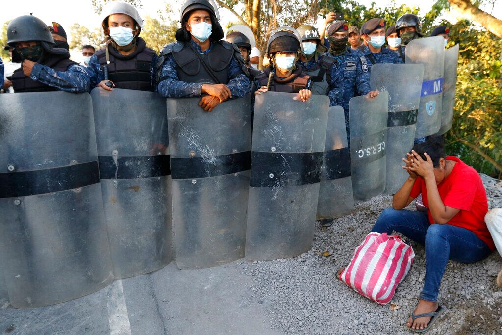 Soldados del ejército de Guatemala frenan a migrantes que formaban parte de una caravana que partió de Honduras con la esperanza de llegar a Estados Unidos, luego de cruzar la frontera en Puerto Barrios, Guatemala