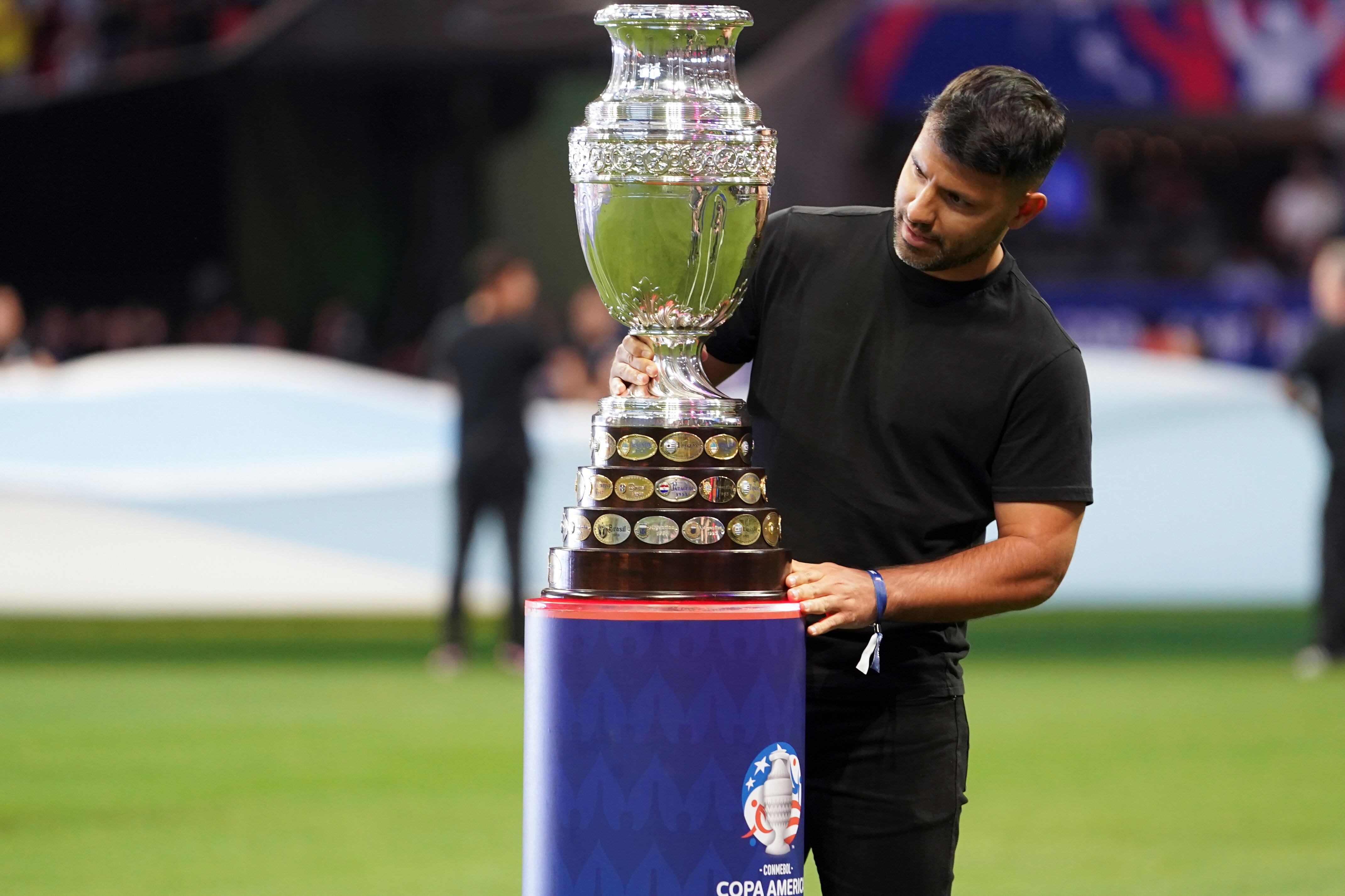 Sergio Agüero, exjugador de la selección argentina, mirando de cerca el trofeo de la Copa América el día de la inauguración del torneo. (AP)