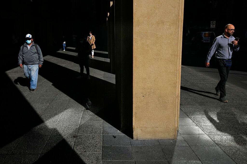 Un transeúnte, con mascarilla por la pandemia del coronavirus, en una calle del centro de Santiago, Chile, el 5 de abril de 2022. Chile relajará sus restricciones sanitarias a partir del 14 de abril, cuando el cubrebocas dejará de ser obligatorio en espacios abiertos. (AP Foto/Esteban Félix)