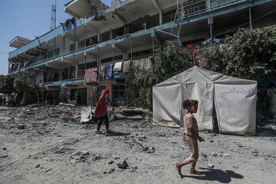 Unos niños palestinos caminan por el patio de una escuela de la UNRWA destruida tras un ataque aéreo israelí en el campo de refugiados de Al Nusairat, en el centro de la Franja de Gaza, este 6 de junio. EFE/EPA/Mohammed Saber