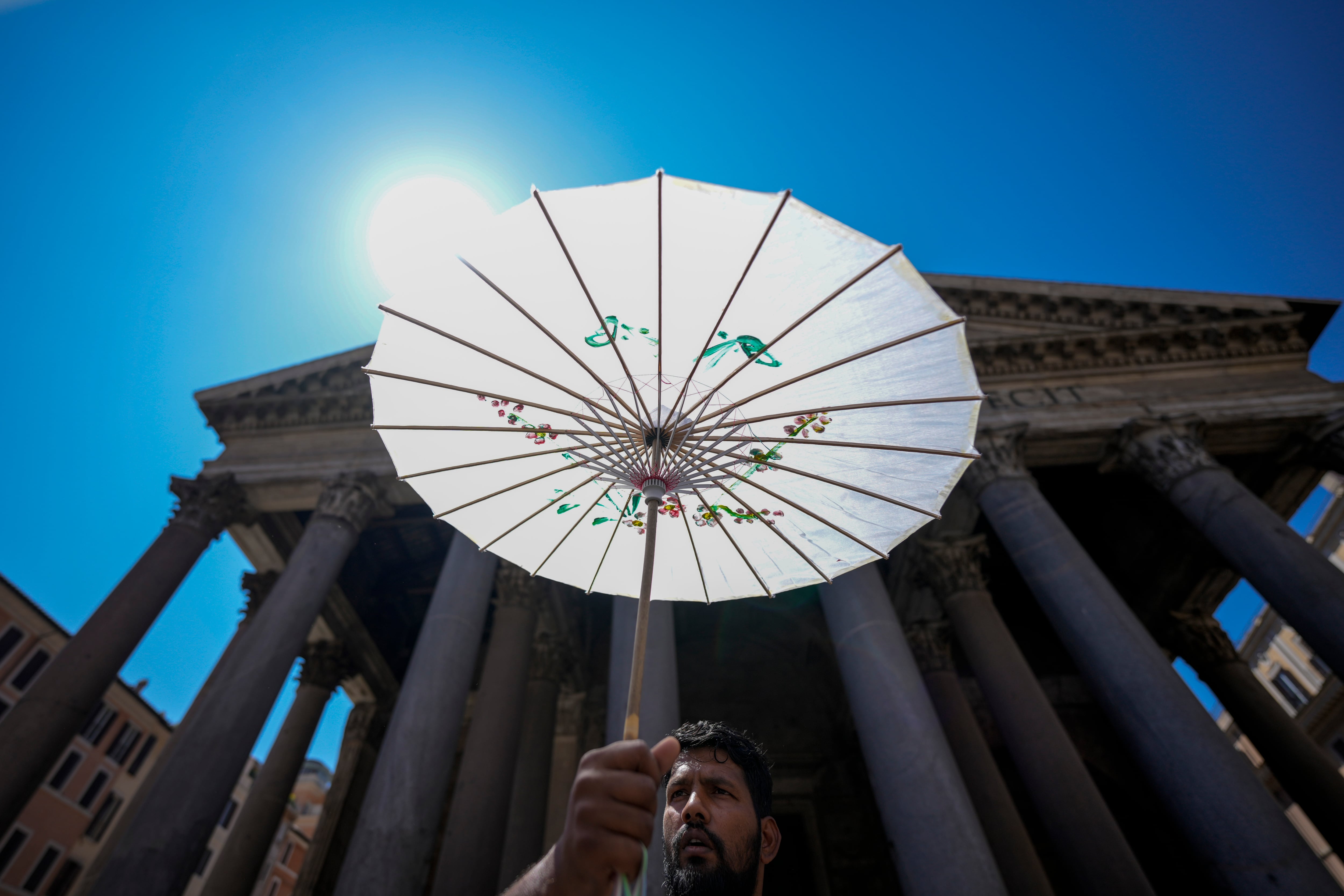 Un hombre se protege del sol con una sombrilla de papel frente al Panteón de Roma durante una ola de calor, el jueves 11 de julio de 2024. (AP Foto/Andrew Medichini)