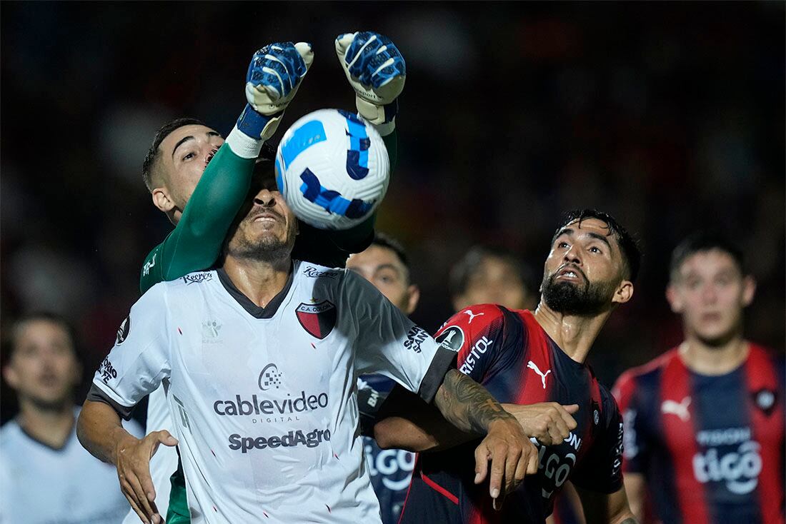 El arquero Jean Fernandes, del Cerro Porteño de Paraguay, despeja un balón sobre Paolo Goltz, del Colón de Santa Fe argentino, ante la mirada de su compañero Alberto Espinola (derecha), durante un juego de la fase de grupos de la Copa Libertadores en el estadio General Pablo Rojas en Asunción, Paraguay, el 12 de abril de 2022. (AP Foto/Jorge Sáenz)