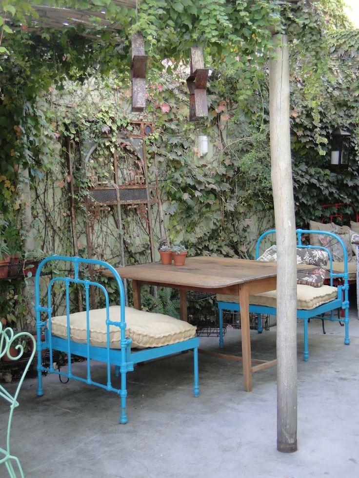 Una cama de hierro antigua que se transformó en dos cómodos sillones, con una mesa clásica de madera. La unión de estilos marca la diferencia en la decoración.