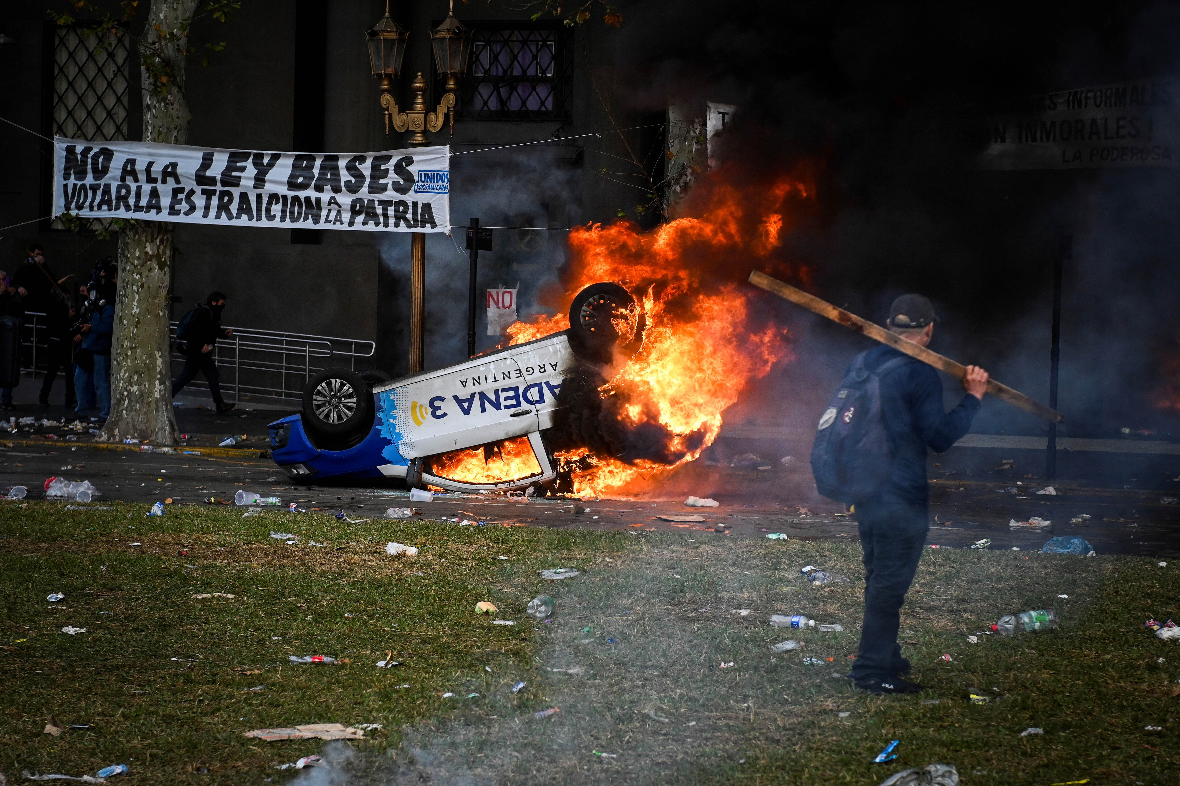 El móvil de Cadena 3 arde durante la protesta cerca del Congreso Nacional, el día en que los senadores debaten el proyecto de reforma económica del presidente argentino Javier Milei, conocido como Ley Bases. Foto NA: REUTERS/Mariana Nedelcu