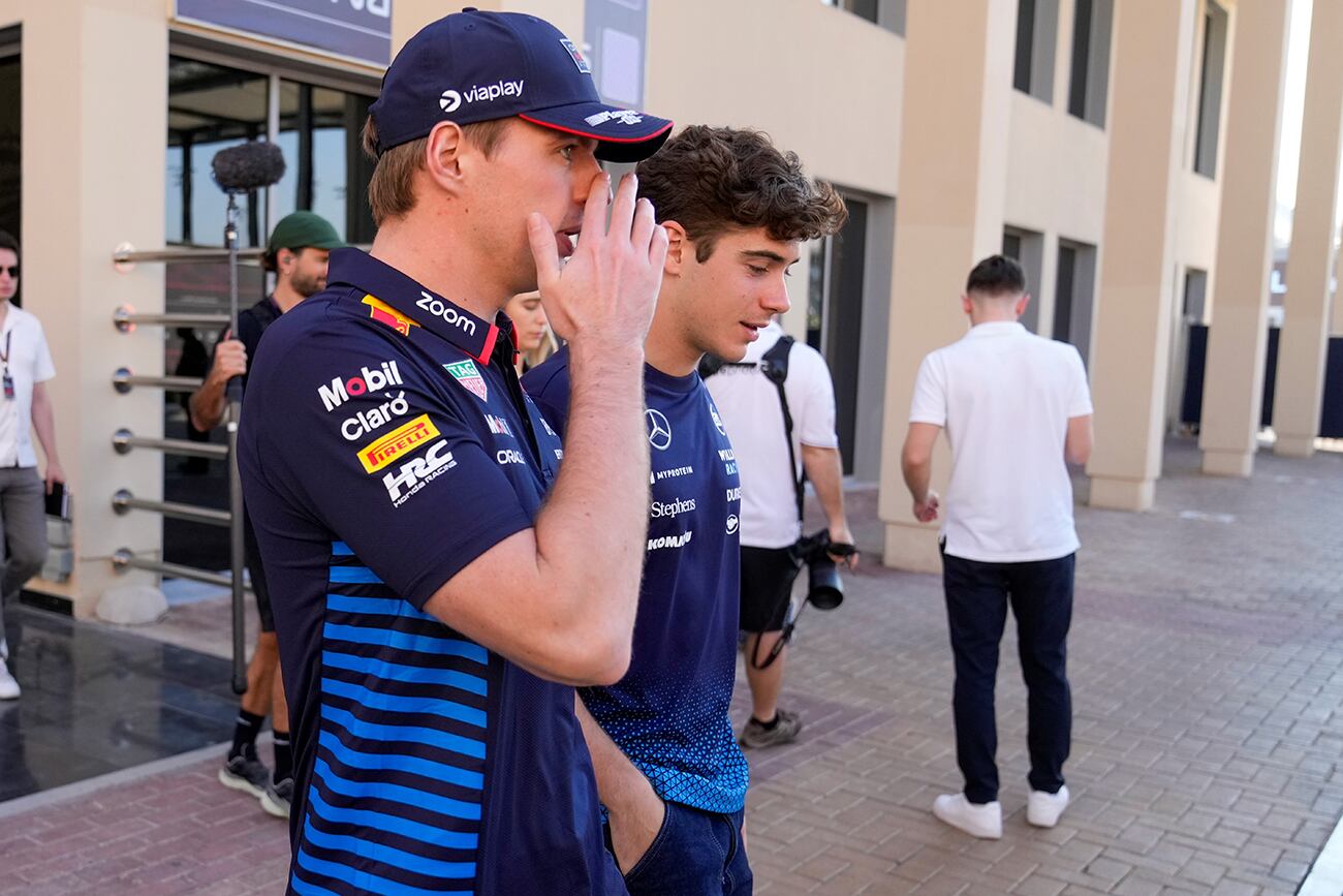 El piloto de Red Bull, Max Verstappen de Holanda, a la izquierda, habla con el piloto de Williams, Franco Colapinto de Argentina, mientras caminan por el paddock antes del Gran Premio de Fórmula Uno de Abu Dabi, en el Circuito Yas Marina en Abu Dabi, Emiratos Árabes Unidos, el jueves 5 de diciembre de 2024. (Foto AP/Darko Bandic)