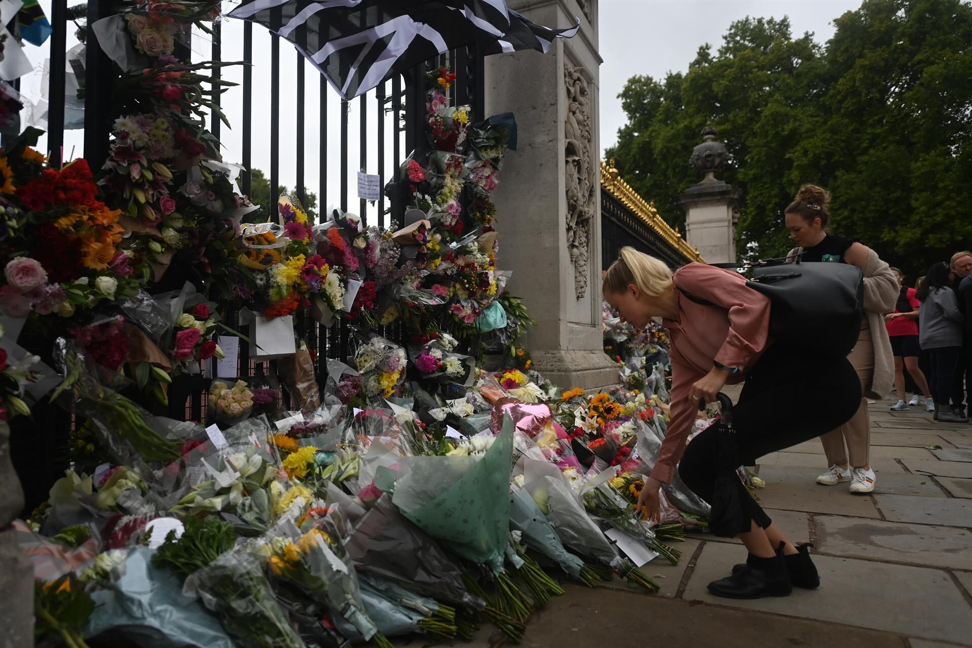 Una mujer deposita flores este viernes frente al palacio de Buckingham en Londres tras la muerte de la reina Isabel II. El 19 de septiembre será el funeral. / Foto: EFE