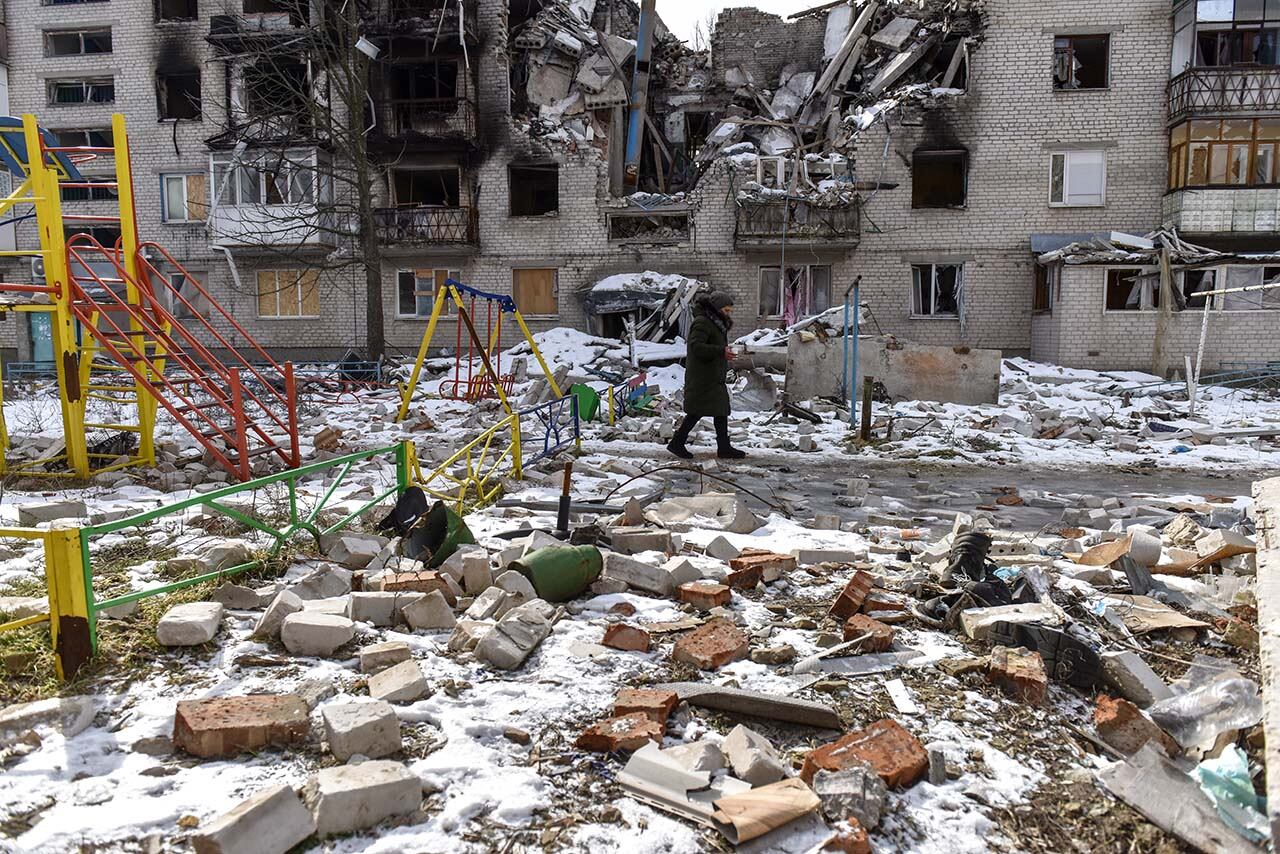 Una mujer pasa frente a un edificio dañado en Sviatohirsk, región de Donetsk. Foto: EFE