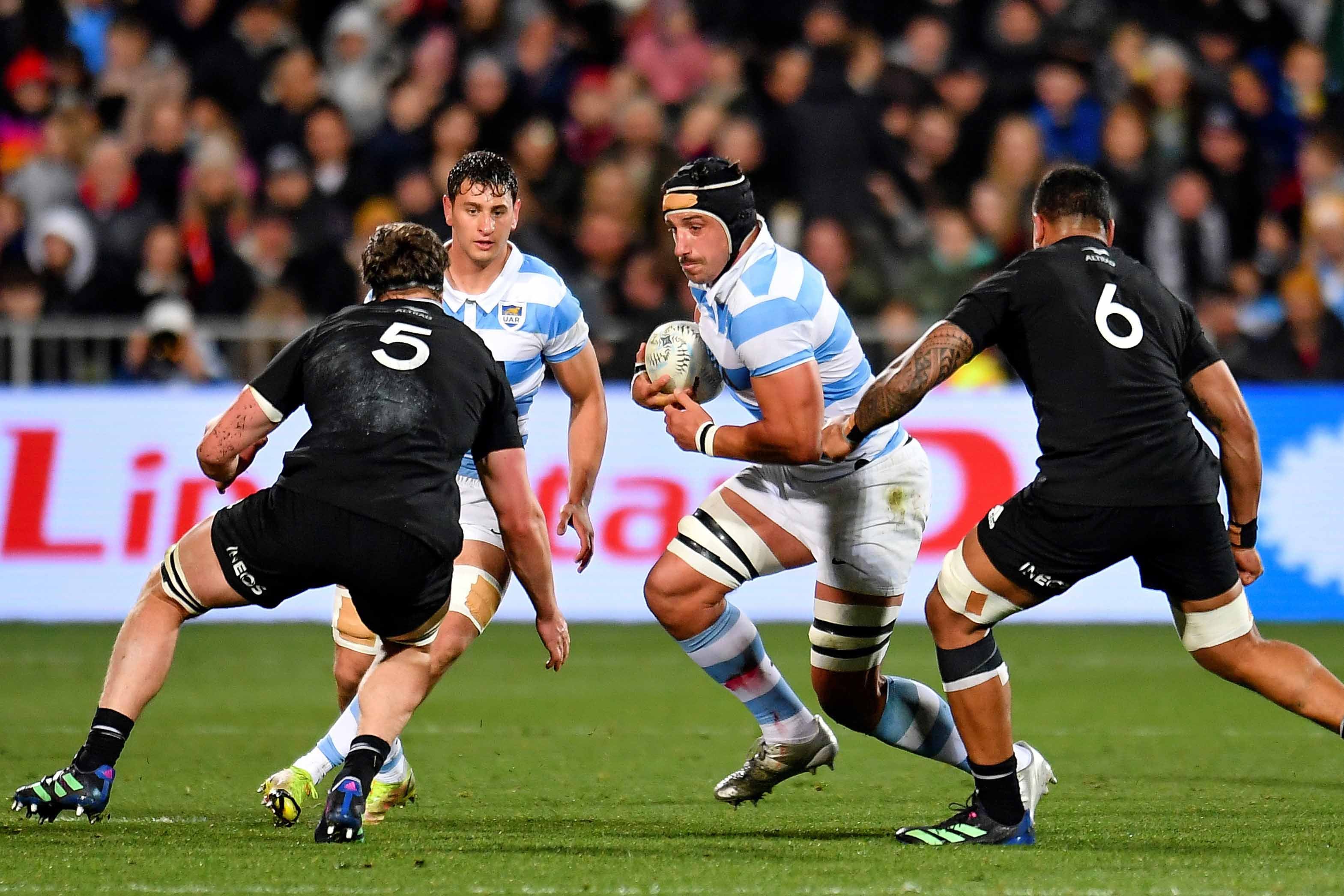 Tomás Lavanini encara entre dos All Blacks.