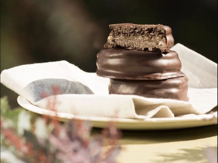 El relleno se elabora con una pasta a base de porotos y almendras, ofreciendo una untuosidad y sabor similares a los originales de dulce de leche. 