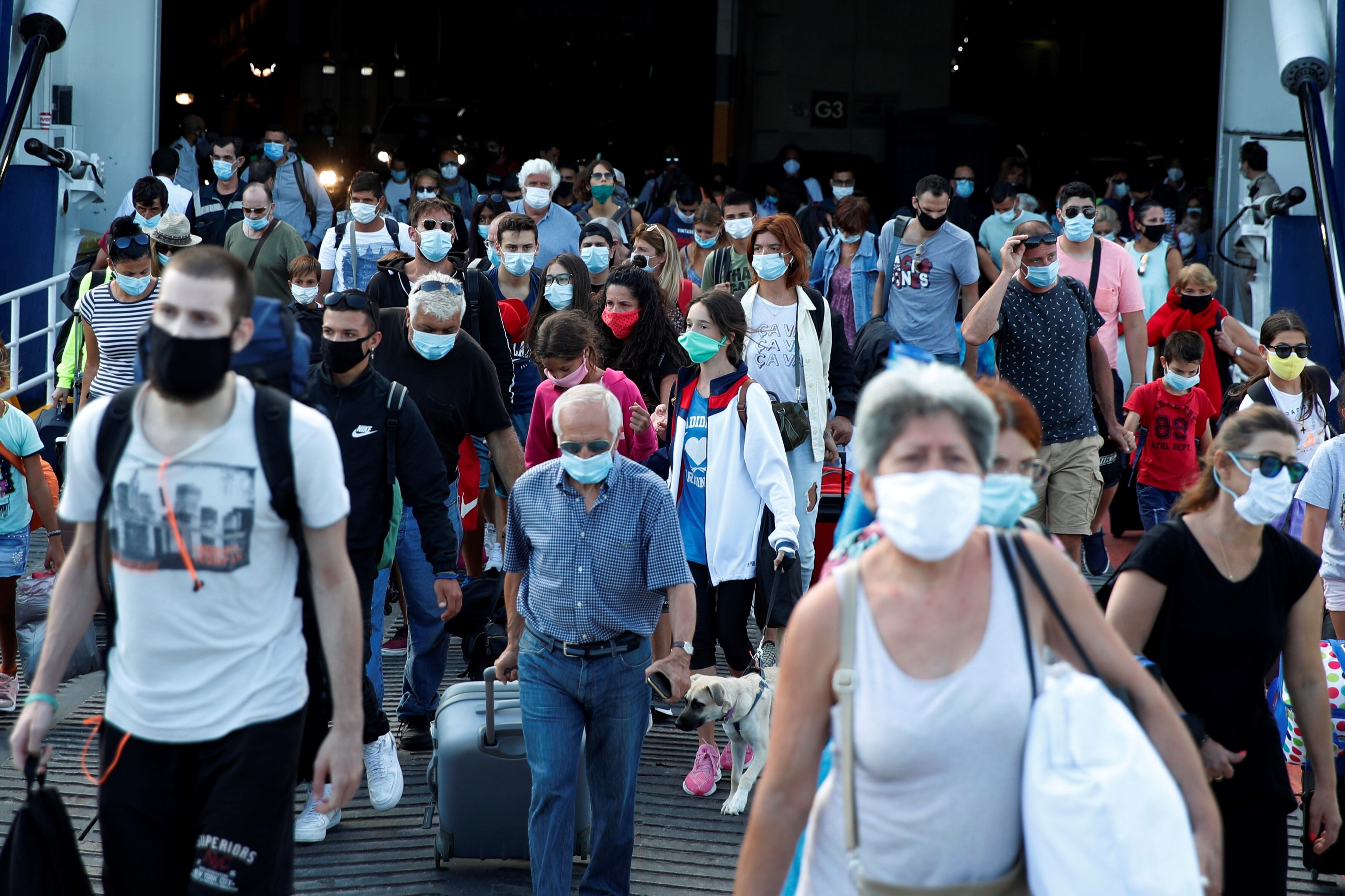 Viajeros con mascarillas contra la propagación del nuevo coronavirus, desembarcan de un ferry en el puerto de El Pireo, cerca de Atenas. AP