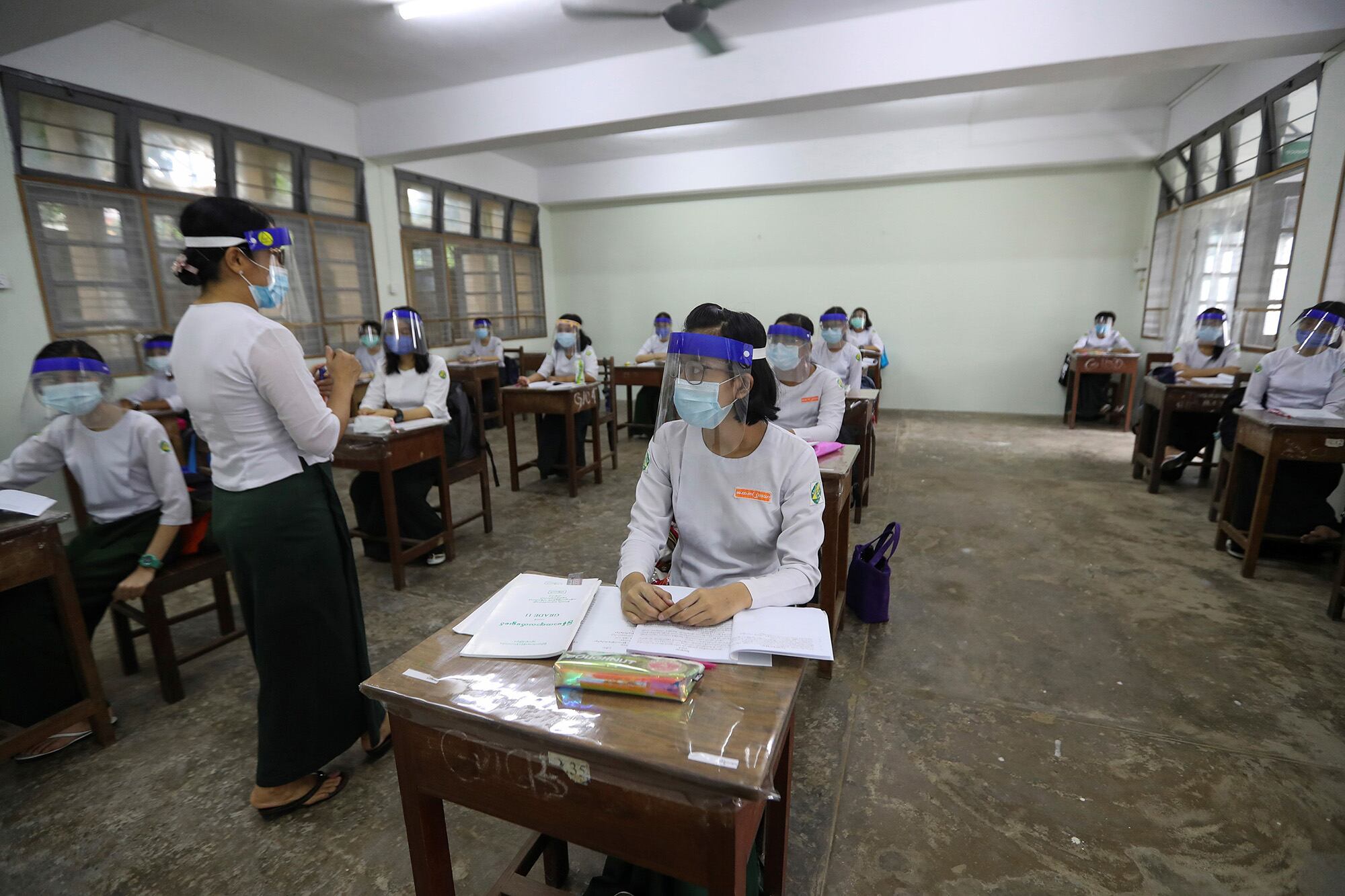 Estudiantes asisten a clases manteniendo el distanciamiento social en una escuela secundaria en Yangon, Myanmar.