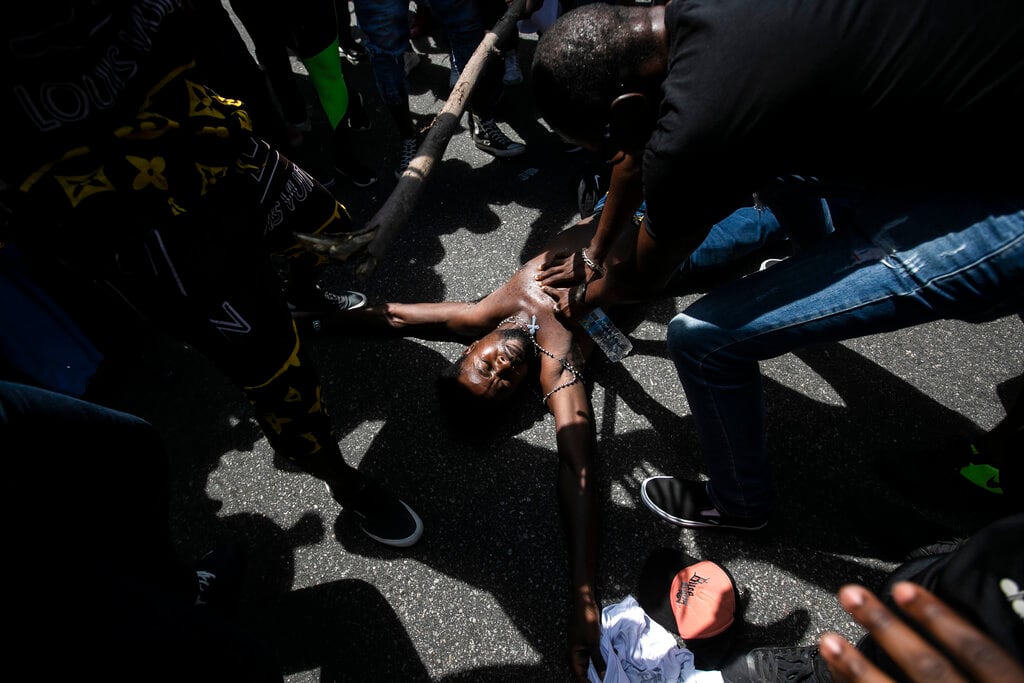 Un manifestante simula la muerte violenta de un inmigrante congoleño asesinado por una supuesta disputa por un pago en Río de Janeiro, Brasil, el 5 de febrero de 2022. El deceso de Moïse Mugenyi Kabagambe, de 24 años, causó conmoción en todo el país luego de que los agresores fueron grabados por las cámaras de seguridad atacándolo, sujetándolo y pegándole con una vara incluso después de perder la consciencia. (AP Foto/Bruna Prado)