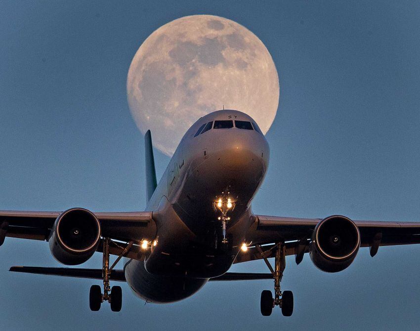 
    Un avión se acerca al aeropuerto cuando sale la luna . (Foto de AP / Michael Probst)
   