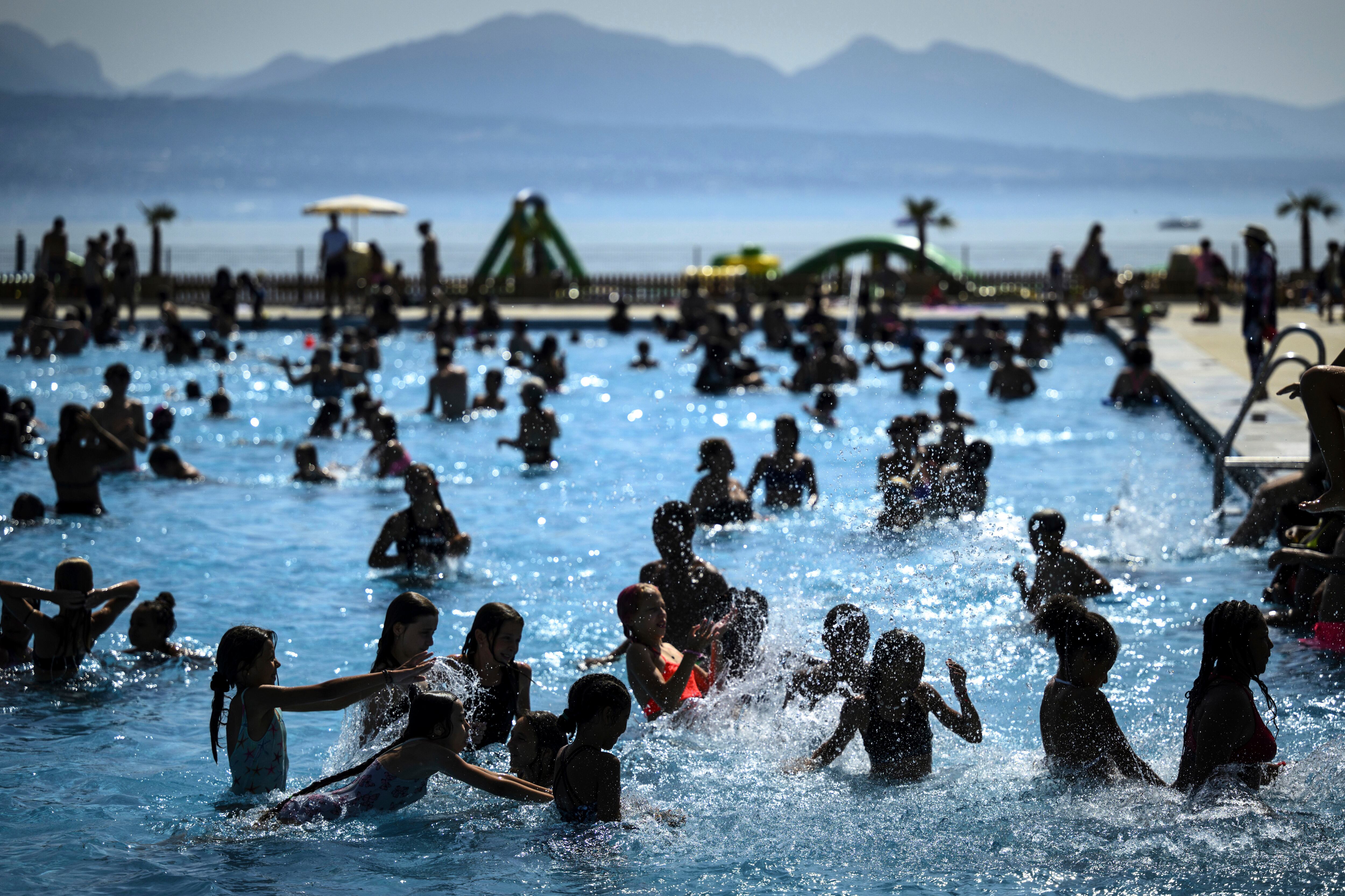 Personas tratando de evadir el calor en una piscina en Bellerive a orillas del Lago Ginebra, en Lausana, Suiza, el 23 de agosto de 2023.. (Laurent Gillieron/Keystone via AP)