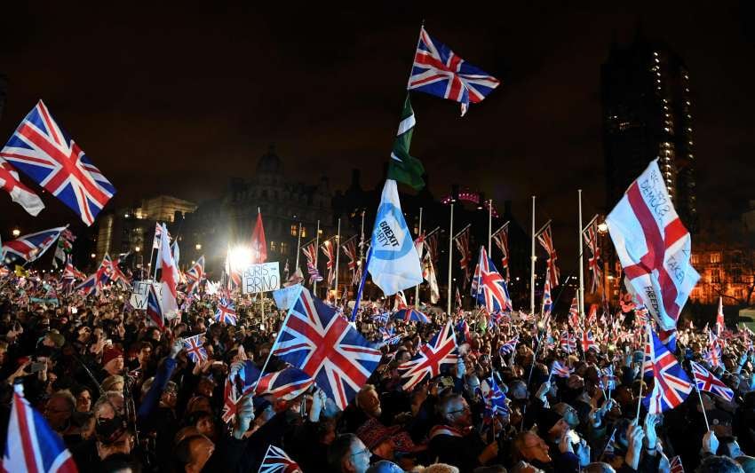 
Los partidarios del Brexit ondean banderas de la Unión cuando el tiempo llega a las 11 en punto, en la Plaza del Parlamento | AFP
   