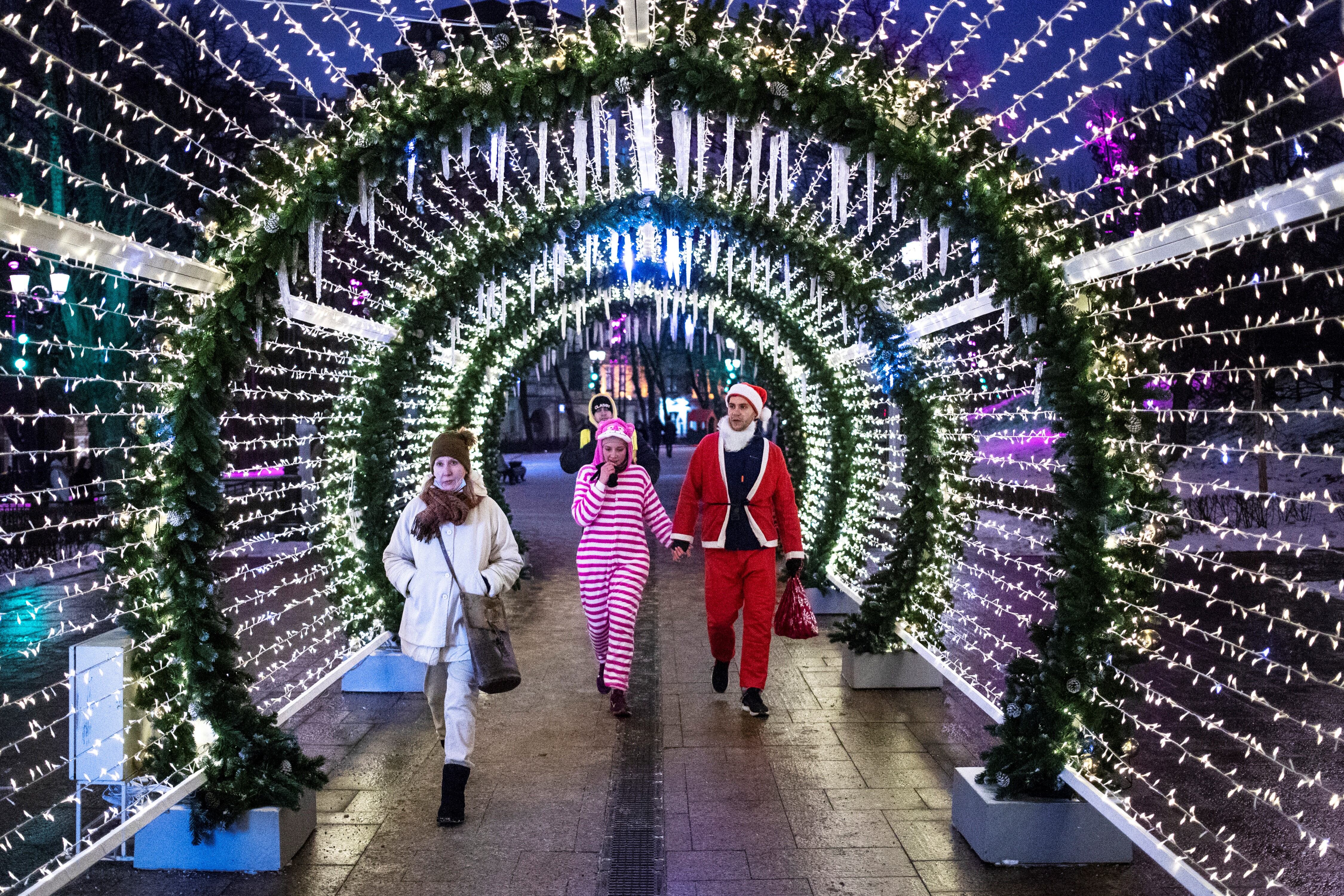 Una pareja vestida con trajes de Navidad camina dentro de las decoraciones instaladas para celebrar la próxima Navidad y Año Nuevo en Moscú, Rusia.