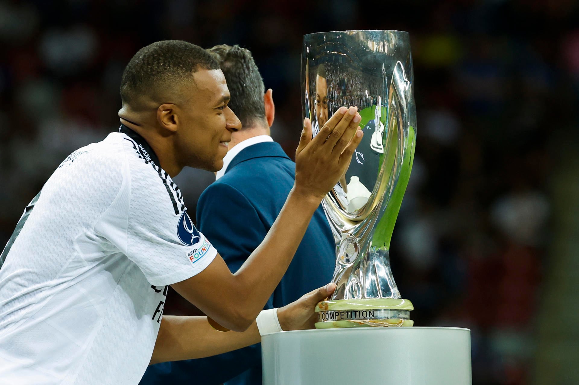 El delantero del Real Madrid Kylian Mbappé acaricia el trofeo tras la disputa de la Supercopa de Europa de fútbol que Real Madrid y Atalanta jugaron este miércoles. EFE/ Mariscal