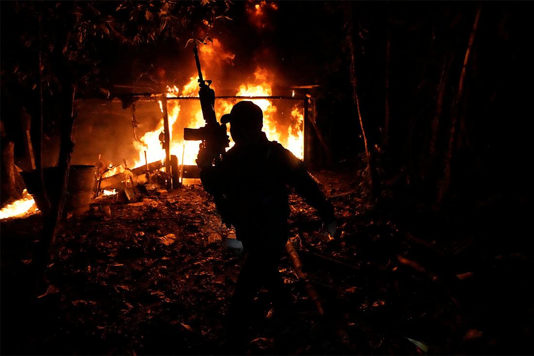 Policías antinarcóticos queman un laboratorio para fabricar base de coca, el producto intermedio del proceso de transformación de la hoja de coca en cocaína, en Orito, en el estado de Putumayo, Colombia, el 9 de abril de 2022. (AP Foto/Fernando Vergara)