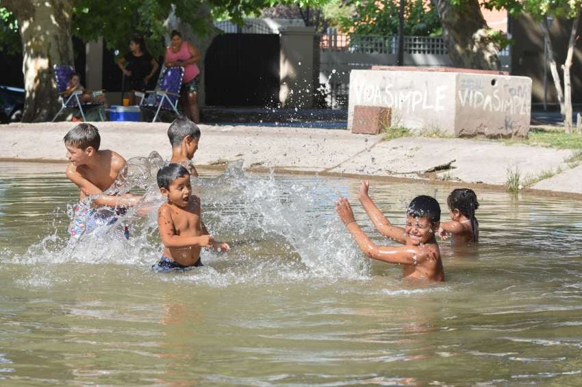 
¡Al agua! Un grupo de primos se refresca mientras su tía Jesica González los cuida desde la orilla de la lagunita frente al acceso Este. | Orlando Pelichotti / Los Andes
   