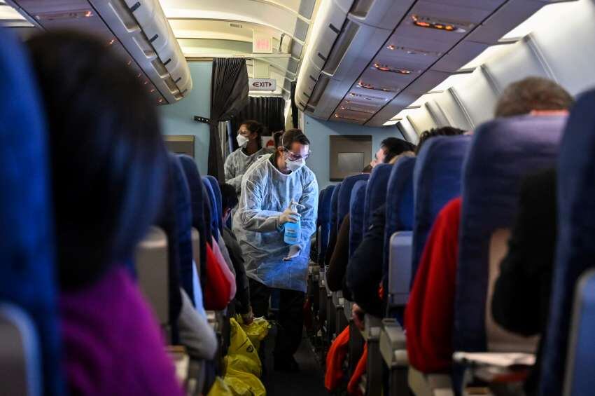 
Un miembro de la tripulación de un vuelo de evacuación de ciudadanos franceses desde Wuhan les da desinfectantes a los pasajeros durante el vuelo a Francia. | AFP
   