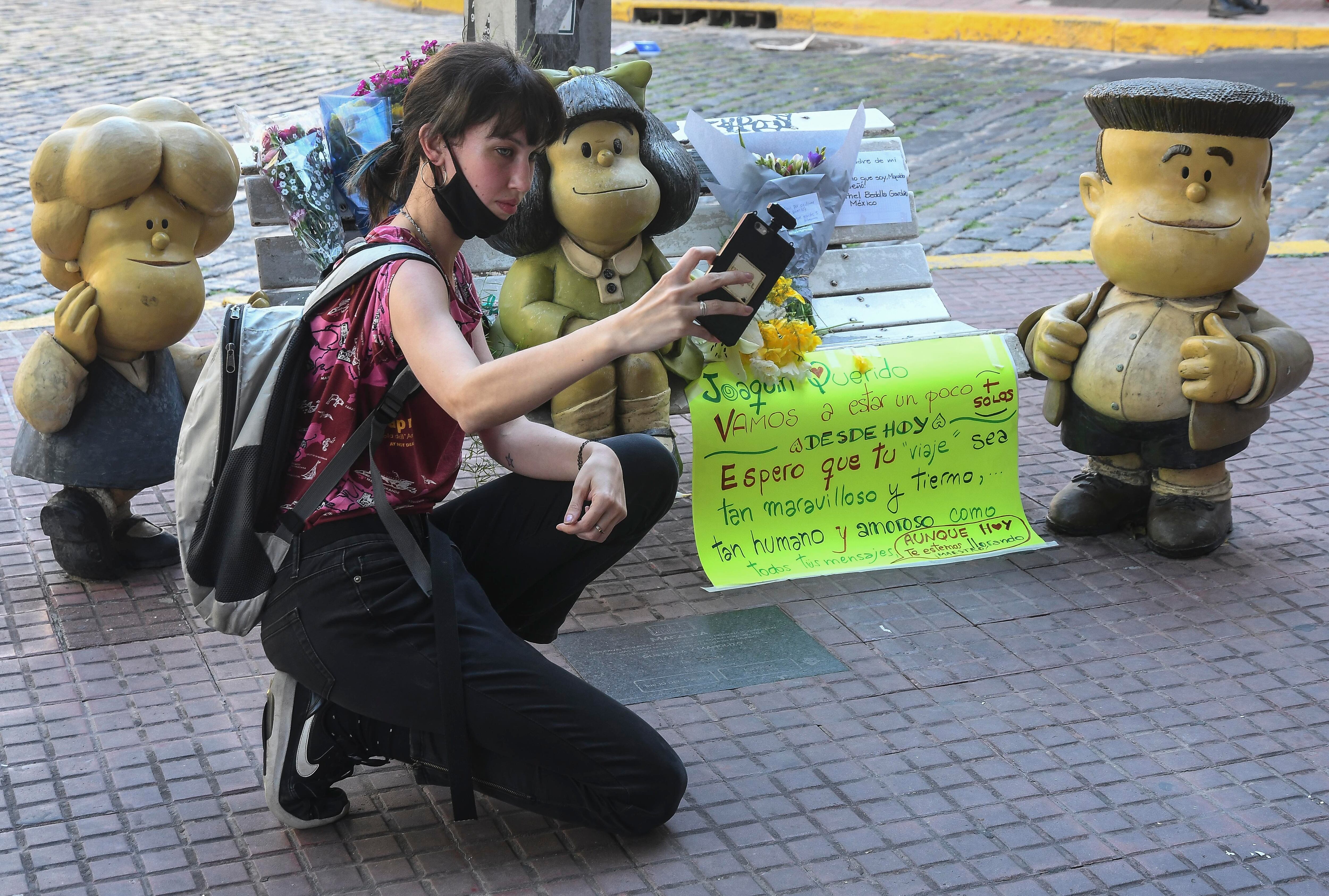 Flores y selfies en la escultura de Mafalda sentada en un banco de plaza en el barrio porteño de San Telmo.