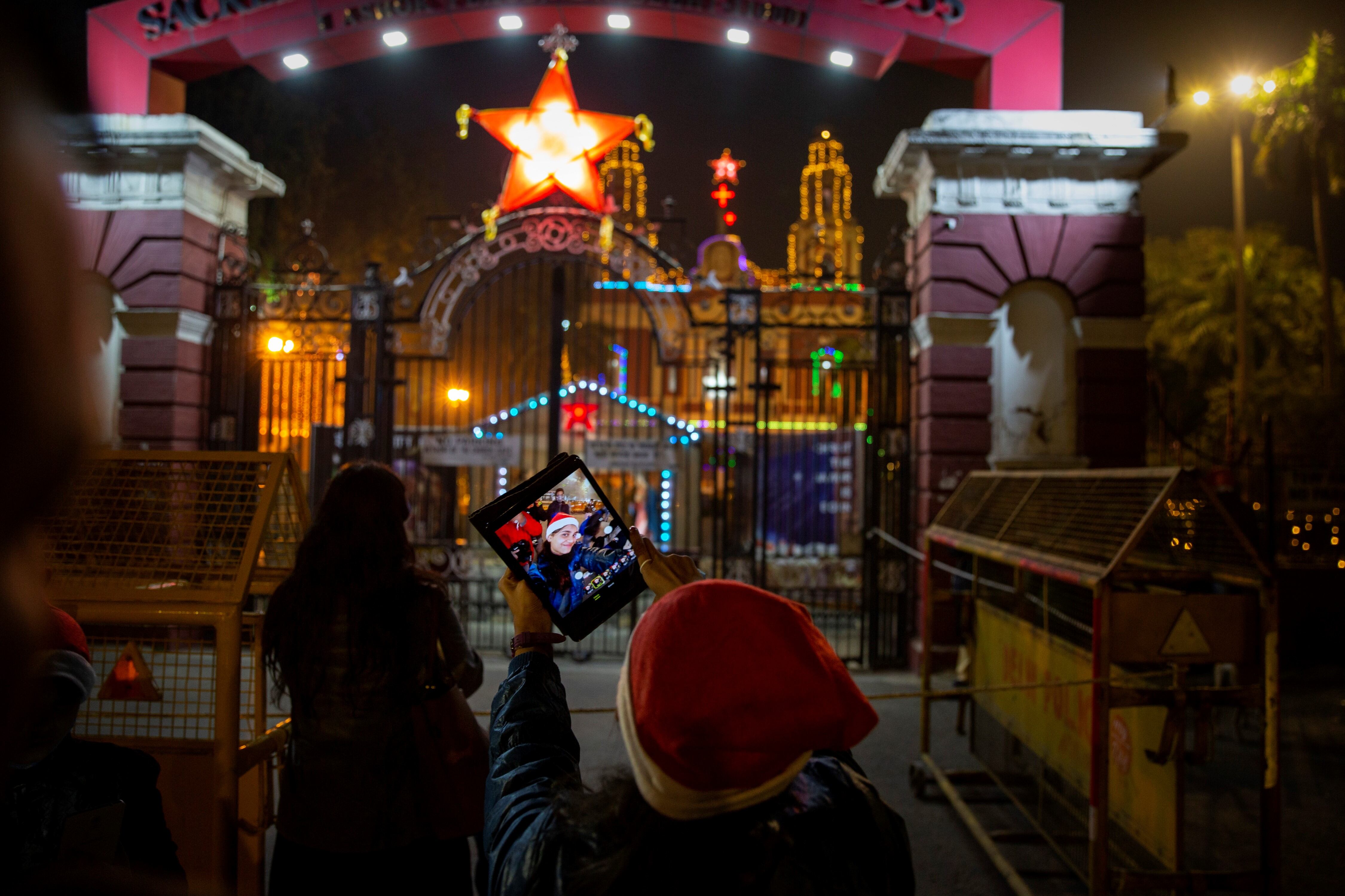 Una niña india se toma una selfie frente a la Catedral del Hogar Sagrado, que está cerrada al público en general debido a las restricciones de COVID-19 en la víspera de Navidad en Nueva Delhi, India.