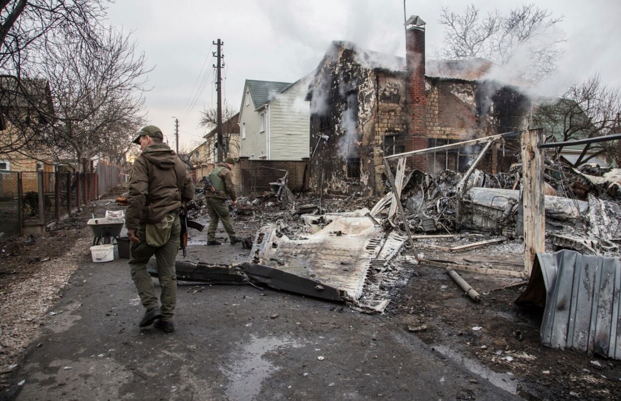 Militares ucranianos caminan frente a los fragmentos de un avión derribado en Kiev, Ucrania. (AP)