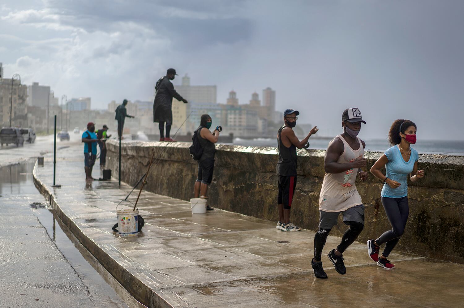 Una pareja trota bajo la lluvia en el malecón, en La Habana, Cuba.