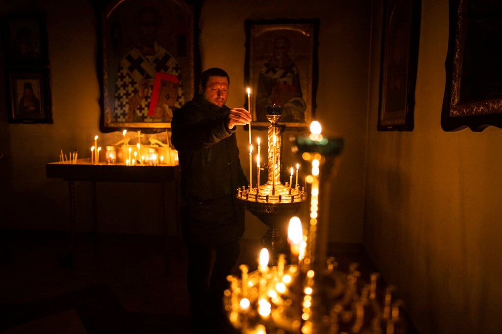 Un hombre enciende una vela durante un servicio religioso en una iglesia ortodoxa, el domingo 10 de abril de 2022, en Bucha, a las afueras de Kiev, Ucrania. (AP Foto/Rodrigo Abd)