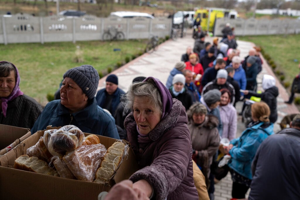 Varias personas hacen fila para recibir alimentos de una iglesia, el domingo 10 de abril de 2022, en la localidad de Borodyanka, al noroeste de Kiev, Ucrania. (AP Foto/Petros Giannakouris)