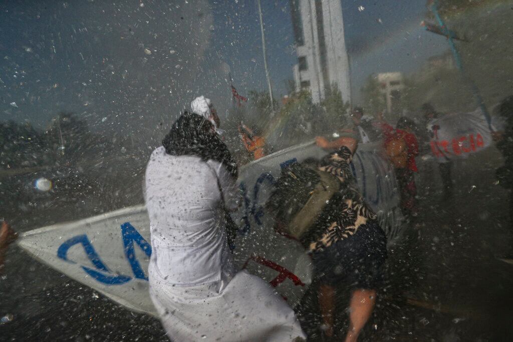 Una monja, empapada por los cañones de agua empleados por la policía para dispersar a manifestantes antigubernamentales que protestan contra la desigualdad dos días antes de un referéndum sobre la reforma de la Constitución chilena, que data de la dictadura militar de Augusto Pinochet, en Santiago, Chile.