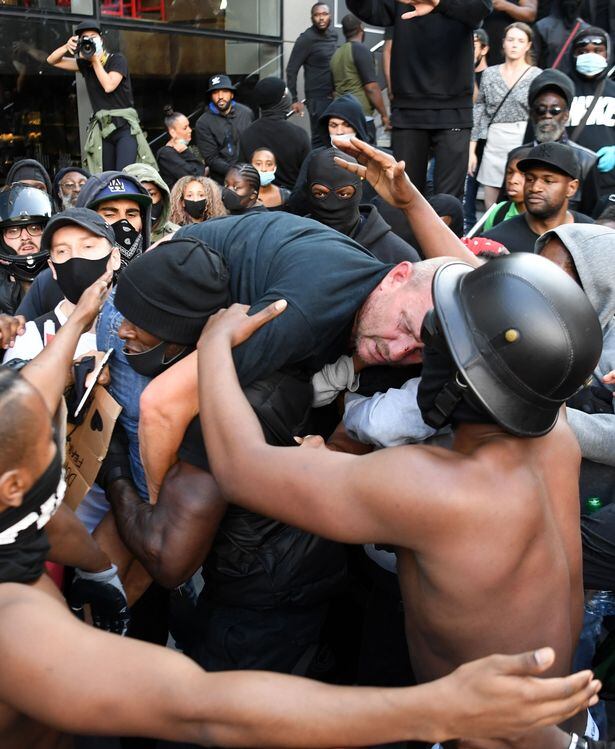 El manifestante negro Patrick Hutchinson retira en sus hombros a otro blanco que había quedado lastimado tras los enfrentamientos.